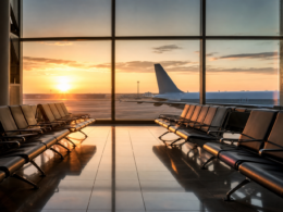 Empty airport departure gate seating at sunrise with a jet bridge visible through the window