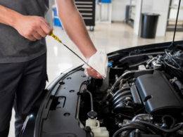 A person checking the oil dipstick in an open car engine bay