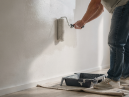 A person painting a wall with a roller during a home improvement project