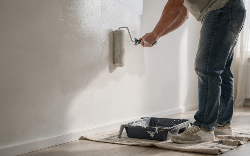 A person painting a wall with a roller during a home improvement project