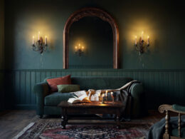 Moody fantasy inspired living room with deep green walls, arched mirror, and warm candlelight