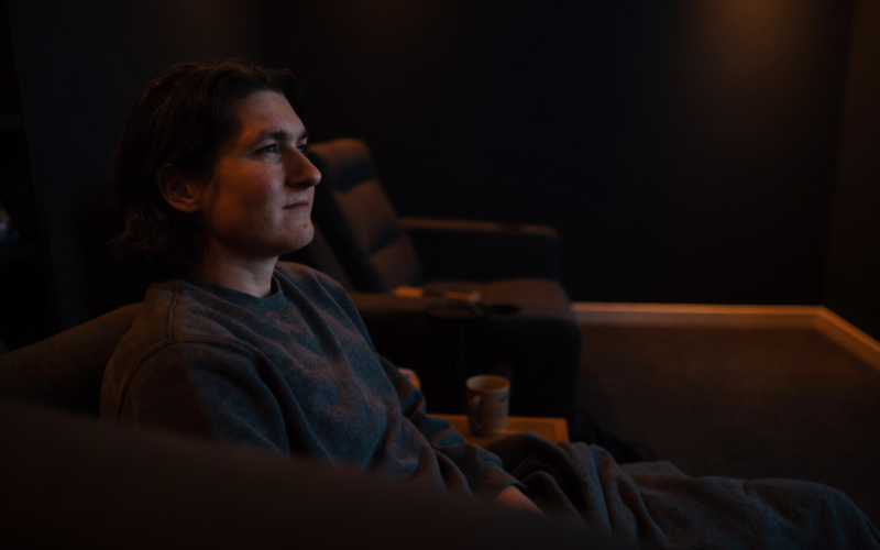 A person watching a film thoughtfully in a cozy home cinema setting