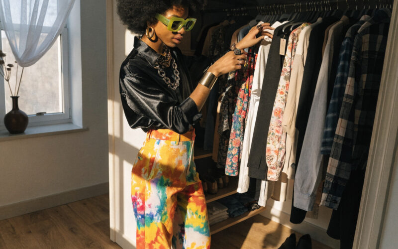 A stylish person choosing clothes from an open closet