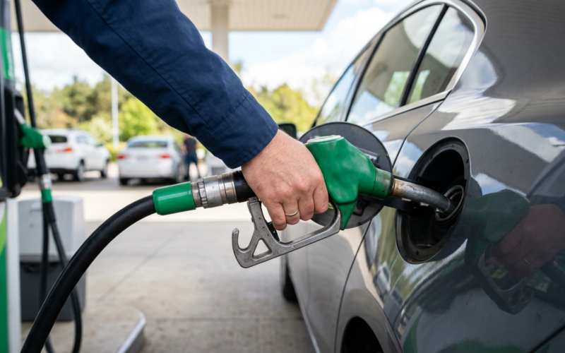 A hand refueling a car at a gas station fuel pump