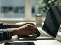 Hands on a laptop keyboard with a loading spinner on screen while troubleshooting a slow computer
