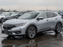 Silver hybrid crossover parked on a wet dealership lot after rain