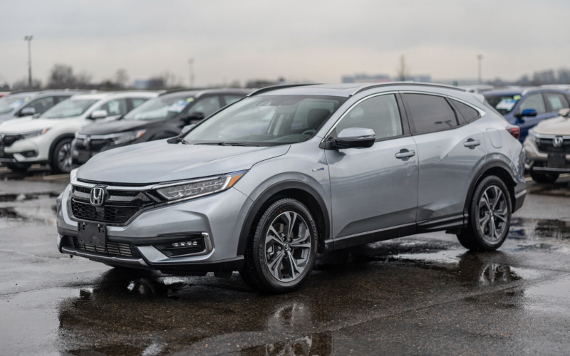 Silver hybrid crossover parked on a wet dealership lot after rain