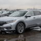 Silver hybrid crossover parked on a wet dealership lot after rain