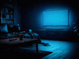 Dim living room at night with a television glowing and a remote on the sofa