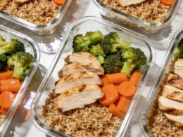 Glass meal prep containers filled with brown rice, roasted vegetables, and grilled chicken on a kitchen counter