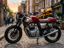 Sleek red cafe racer motorcycle parked on a cobblestone street at golden hour