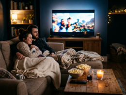 A cozy movie night with a couch, blankets, popcorn, and a glowing TV in a dim room