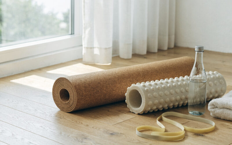 Recovery and mobility gear including a cork mat, foam roller, and resistance band in soft light
