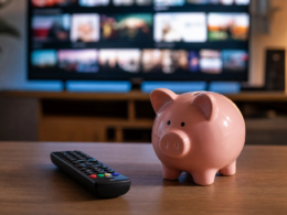 A TV remote beside a piggy bank on a coffee table in front of a television