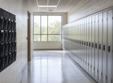 Row of school lockers in an empty hallway with a fabric phone storage pouch hanging beside them