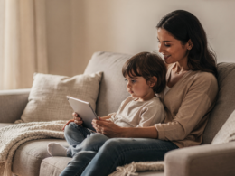 A young child on a couch looking at a tablet while a parent sits nearby