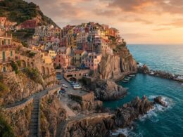 Colorful cliffside coastal village overlooking turquoise water at sunset