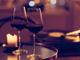 Two glasses of red wine, a glowing candle, and a vinyl record player in warm evening light