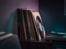 Stack of vinyl record sleeves and a turntable on a wooden surface