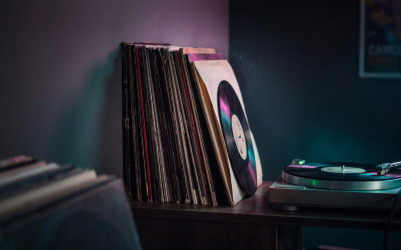 Stack of vinyl record sleeves and a turntable on a wooden surface