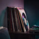 Stack of vinyl record sleeves and a turntable on a wooden surface
