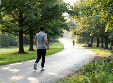 Person walking on a scenic tree-lined path in morning light showing the walking trend