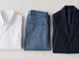 Folded wardrobe essentials including a white shirt, jeans, and a blazer