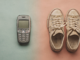 A retro smartphone and vintage sneakers arranged on a split colored surface blending two eras