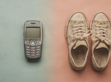 A retro smartphone and vintage sneakers arranged on a split colored surface blending two eras