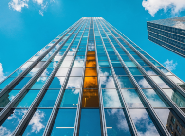 Anthropic IPO concept, worms eye view up a glass tower into blue sky with one amber pane