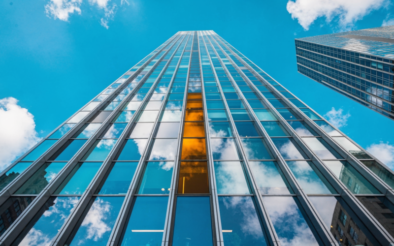 Anthropic IPO concept, worms eye view up a glass tower into blue sky with one amber pane