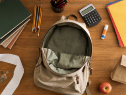 Back to school spending shown as an empty canvas backpack, school supplies and a long blank receipt on a kitchen table