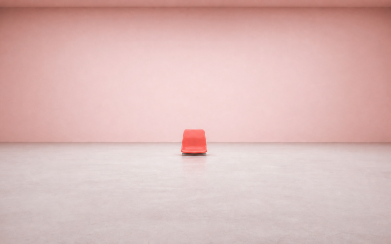 Single vivid coral stadium seat standing alone in a vast empty pale pink room