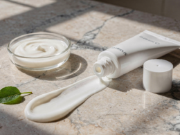 Bemotrizinol sunscreen concept with an unlabeled white tube and a swipe of cream on marble in bright sunlight