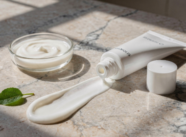 Bemotrizinol sunscreen concept with an unlabeled white tube and a swipe of cream on marble in bright sunlight