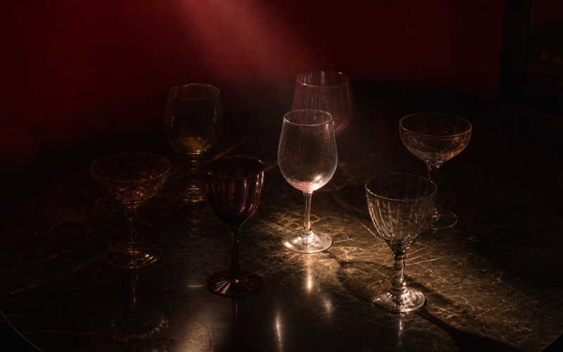 Six mismatched wine glasses on a dark table representing the Pick Your Poison veto competition in the Big Brother 28 episode 12 recap