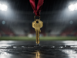 Big Brother 28 Episode 14 recap image showing a brass house key on a red ribbon resting on a wet metal platform under stadium floodlights