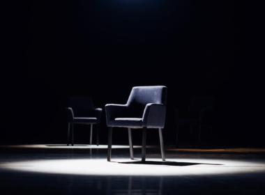 Big Brother 28 recap concept, single empty chair under a hard spotlight with two more in shadow