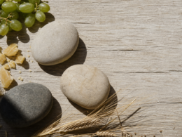 Big Brother 28 recap image of three river stones, grapes and beeswax on sunlit oak planks