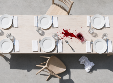 Overhead view of a dining table left mid meal with chairs pushed back and one glass tipped over