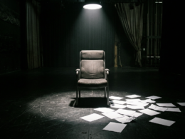 Big Brother 28 eviction illustrated by an empty reality television interview chair under a hard spotlight with paper ballots scattered on a dark studio floor