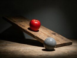 Big Brother 28 eviction concept: a red apple and a stone ball on a wooden ramp under a spotlight