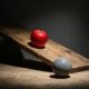 Big Brother 28 eviction concept: a red apple and a stone ball on a wooden ramp under a spotlight