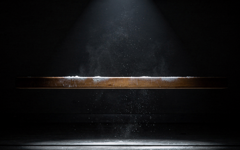 Big Brother 28 Week 7 HOH shown by a narrow wooden balance beam under a single spotlight in a dark room