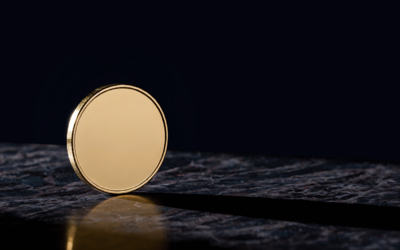 Bitcoin 75000 concept, blank gold coin balanced on edge on dark marble