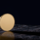 Bitcoin 75000 concept, blank gold coin balanced on edge on dark marble