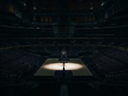 Buss family Lakers stake sale illustrated by a darkened empty arena with a spotlight on center court