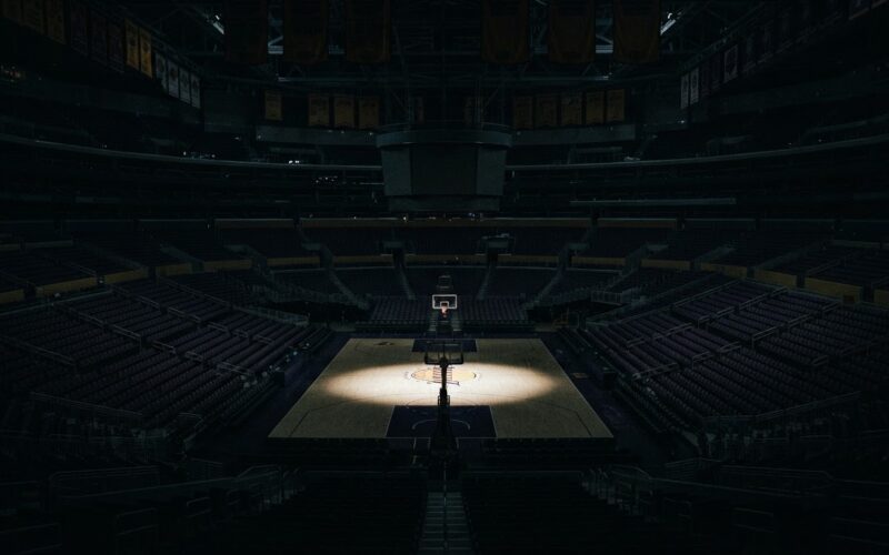 Buss family Lakers stake sale illustrated by a darkened empty arena with a spotlight on center court