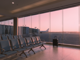 Cheapest week to fly shown as a nearly empty airport departure gate at dawn with a single rolling suitcase