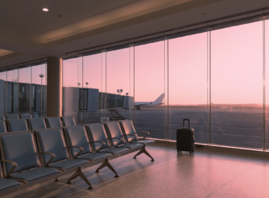Cheapest week to fly shown as a nearly empty airport departure gate at dawn with a single rolling suitcase